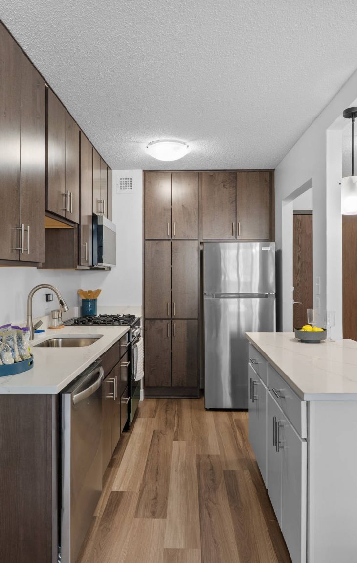 Modern kitchen with wood cabinets, stainless steel appliances, white countertops, and pendant lighting.